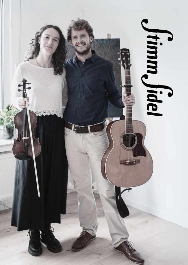Lilith Bodenkamp mit Geige, Christoph Ebel mit Gitarre, beide lächelnd
